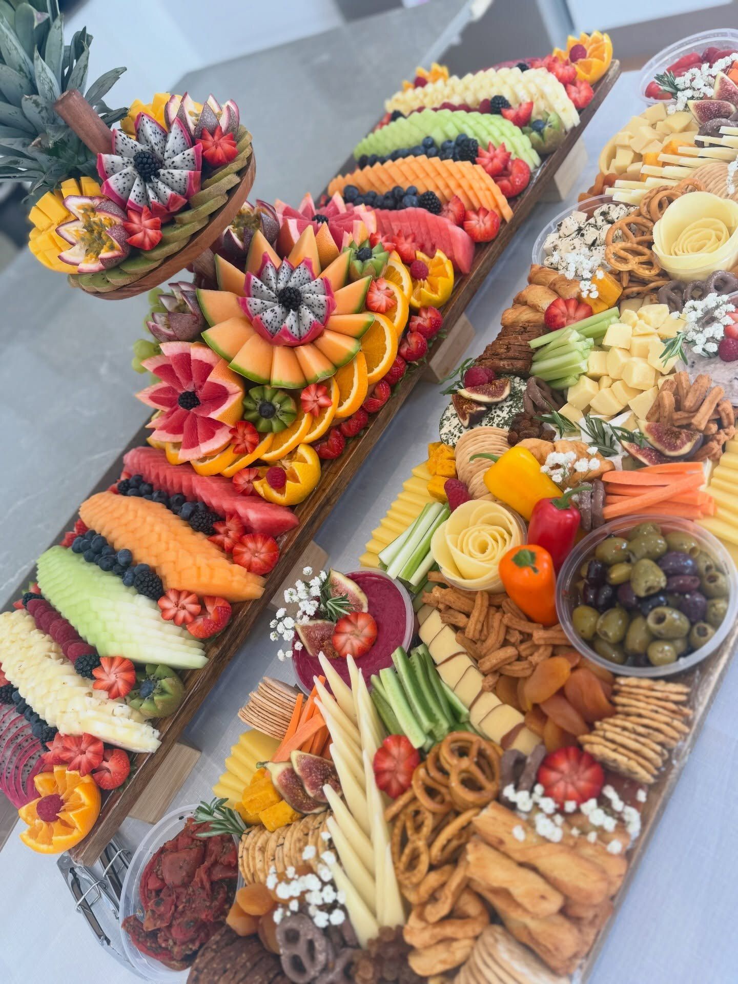 A sculpted fruit board beside a deluxe cheese board