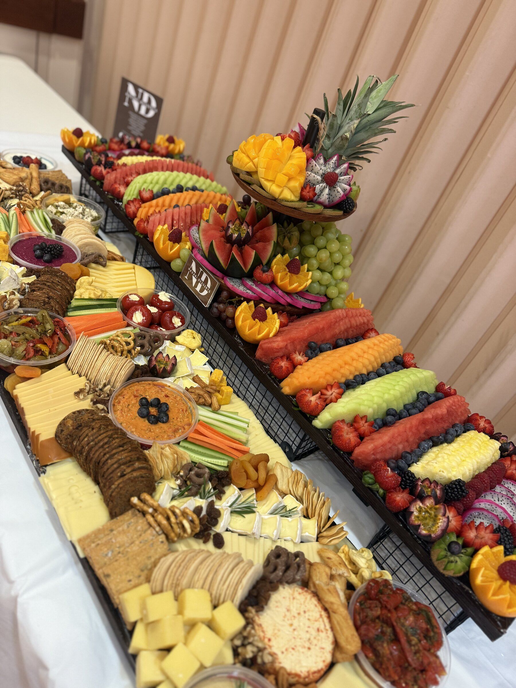 A long grazing table with cheese, olives, dips, crackers and a fruit board