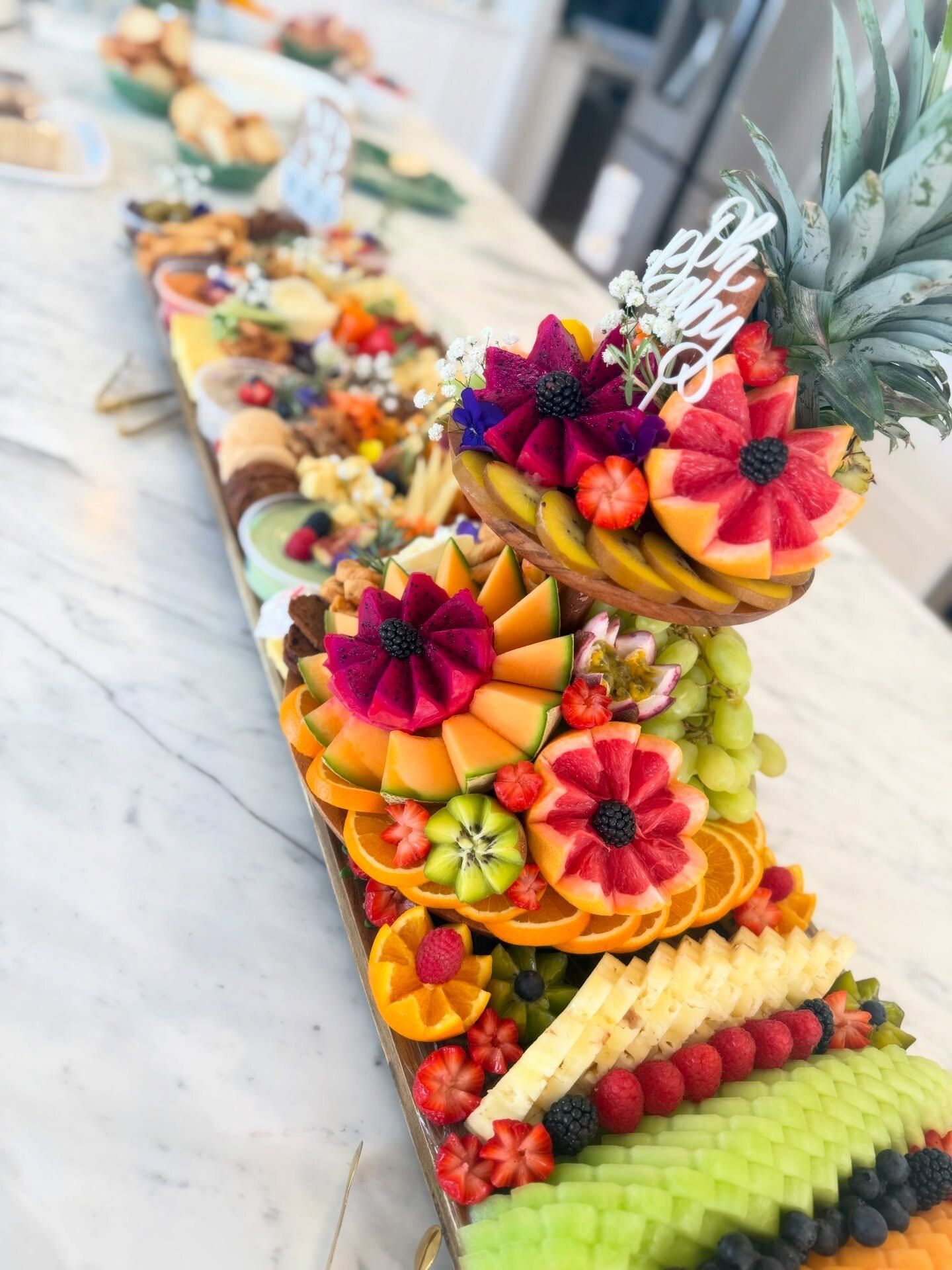 A Half and Half board with a floral fruit tier on marble
