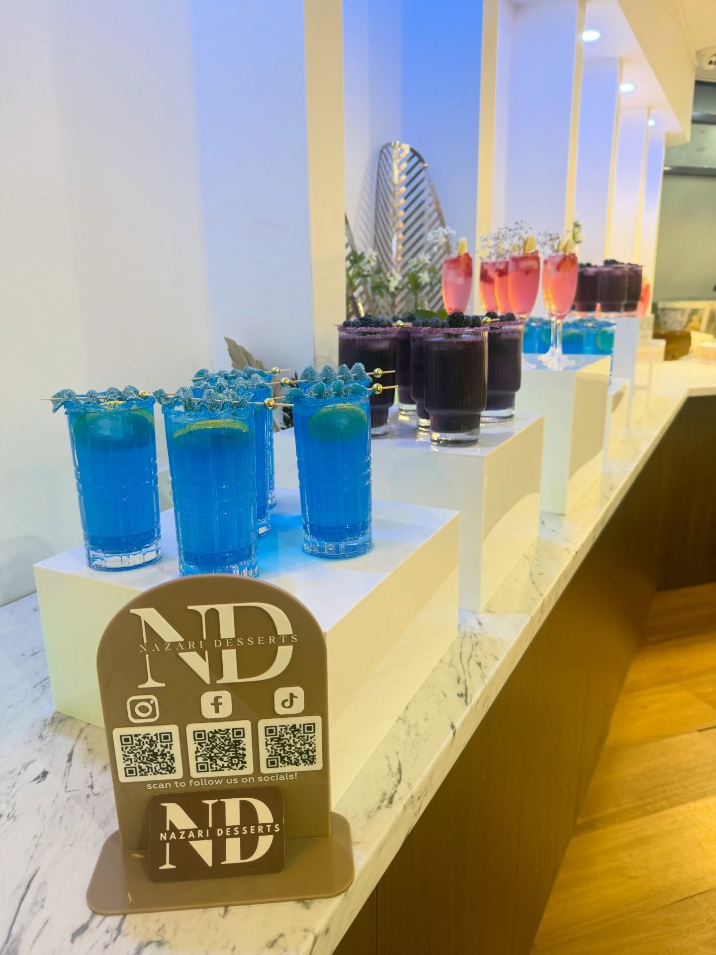 Blue lagoon, pink lemonade and purple punch mocktails on a white bar